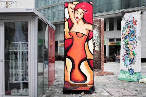 Frauenfigur in Rot auf Berliner Mauer am Checkpoint Charly – Kunst von Ekaterina Moré, Symbol für das Element Feuer.