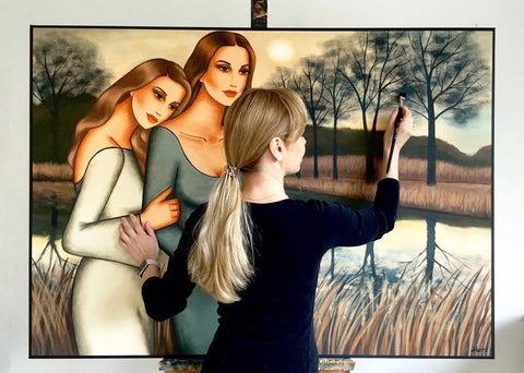 Künstlerin Ekaterina Moré beim Malen eines Frauenbildes mit zwei Figuren in einer stillen Landschaft