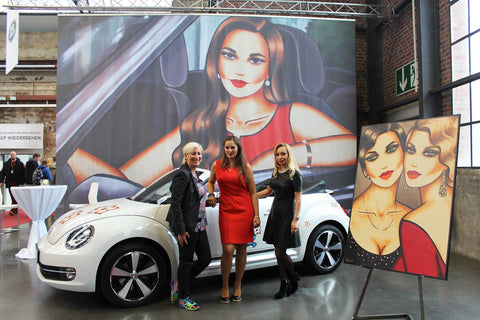 VW Beetle mit femininer Kunst von Ekaterina Moré auf der Automesse – stilvolles Frauenporträt auf der Motorhaube