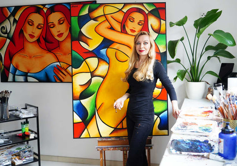 Künstlerin Ekaterina Moré in ihrem Atelier vor farbintensiven Frauenbildern