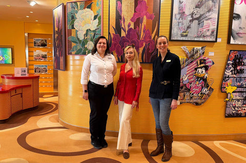 Künstlerin Ekaterina Moré mit dem Galerieteam vor ihren floralen Originalwerken in der Kunstgalerie der AIDAprima