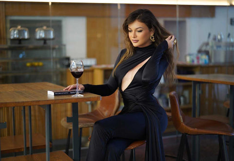 Sasha in schwarzem Kleid mit Glas Rotwein – Coverfoto zum Interview über Weiblichkeit und Identität